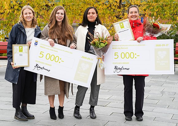 Fyra kvinnor står och håller i två stora prischeckar.