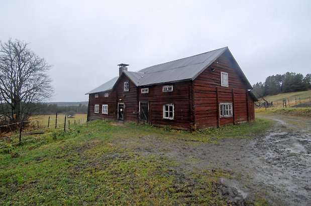 Kläppe 5:18. Ladugård i rött timmer i två våningar, två svarta portar, fönster med vita spröjs.