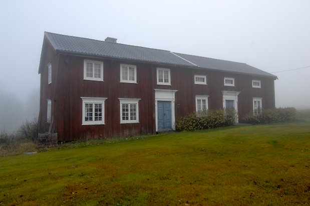 Lungre 1:10. Byggnad i brun panel i två våningar, två blå dubbeldörrar och fönster med vita spröjs.