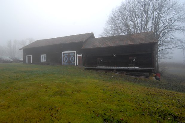 Lungre 1:10. Byggnad i brunt timmer, två röda portar och blå dubbelport med röda kryss. 