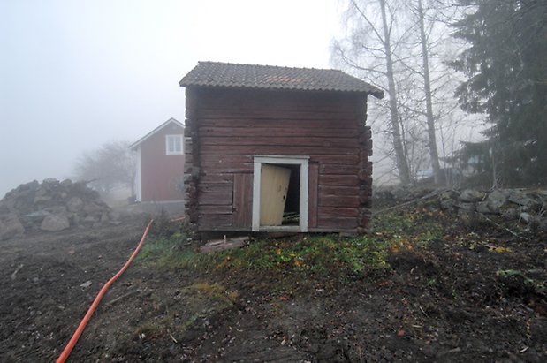 Lungre 2:3. Timrad byggnad med gul port som hänger på sniskan.