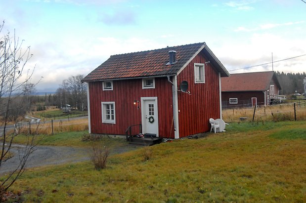 Brynje 1:29. Hus i två våningar i röd panel, vita detaljer, vit dörr och fönster med vita spröjs.