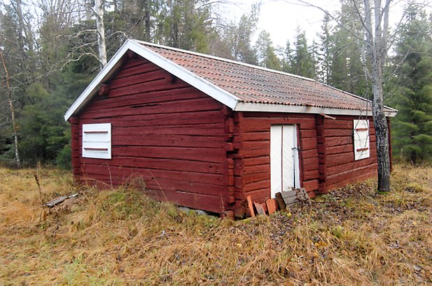 Brynje 2:3. Timrad, röd byggnad med en vit dörr och två vita luckor.