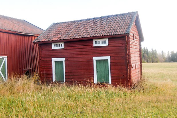 Brynje 2:3. Timrad, röd byggnad med två gröna portar med smala, liggande fönster med vita spröjs ovanför-