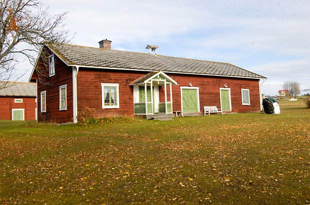 Österåsen 1:32. Hus i två våningar i röd panel med vita detaljer, fönster med gröna spröjs, förstukvist i rött, vitt och grönt, grön dubbeldörr, två gröna dubbelportar.