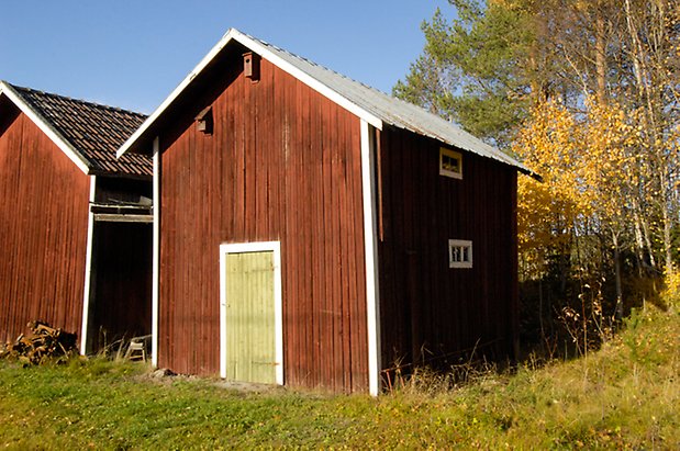 Österåsen 8:15. Byggnad i röd panel med grön port, fönster med spröjs.