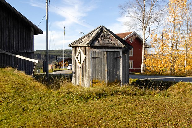 Österåsen 9:23. Sexkantig byggnad i grå panel med går dubbelport.