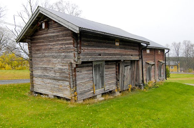 Backegård 1:23. Grå, timrad byggnad, fyra grå portar.