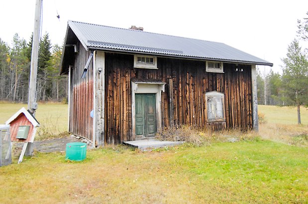 Grötom 1:12. Hus i brun panel med fönster med vita spröjs med grön dubbeldörr.