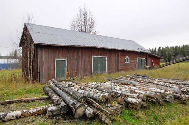 Grötom 1:12. Byggnad i rött timmer och panel, två gröna dubbelportar och två gröna portar, ett vitt fönster med spröjs.