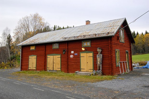 Grötom 1:27. Ladugård i rött timmer med gröna detaljer i två våningar, tre gula dubbelportar, fönster med gula spröjs.