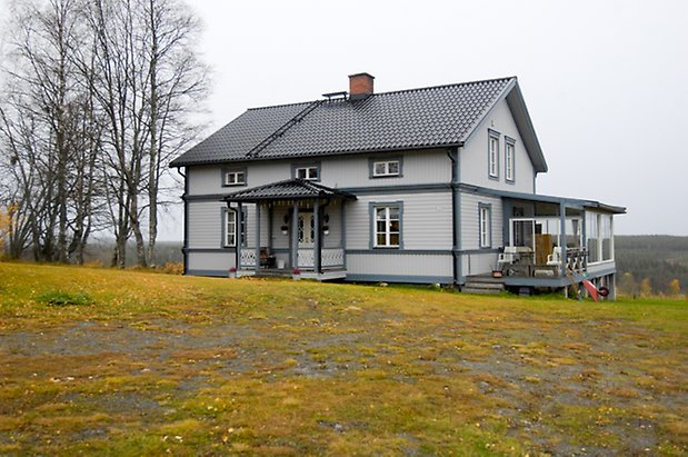 Gungård 3:3. Villa i ljusgrå panel med mörkgrå detaljer, fönster med vita spröjs, förstukvist i mörkgrått och vitt med snickarglädje, inglasad veranda på kortsidan,