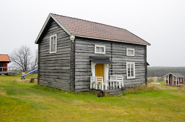 Gungård 4:1. Hus i två våningar i grått timmer, fönster med vita spröjs och gul dubbeldörr.