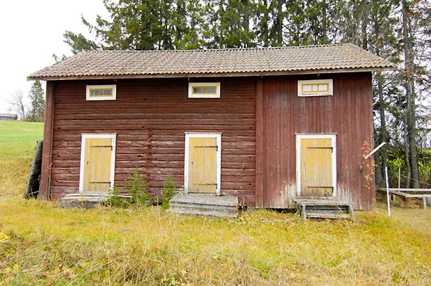 Jonsgård 1:88. Byggnad i röd panel och timmer, tre gula portar.