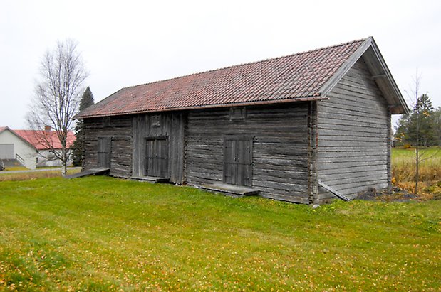 Lassgård 1:28. Byggnad i grått timmer med tre dubbelportar.