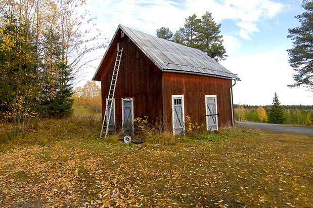 Långkälen 2:7. Byggnad i röd panel med fyra blå portar.