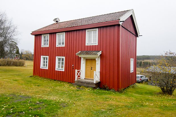 Nygård 1:29. Villa i två våningar i röd panel, fönster med vita spröjs, gul dubbeldörr.