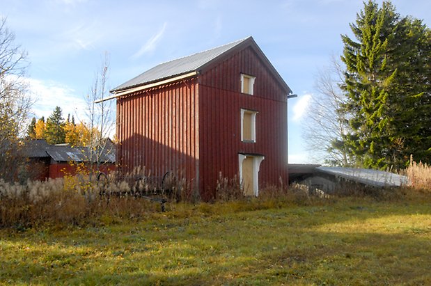 Storhögen 1:6. Byggnad i röd panel och tre våningar, tre gula luckor.