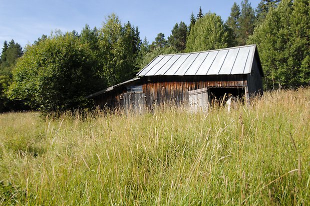 Kungsgården 5:4. Byggnad i brun/grå panel med port som hänger på sniskan.