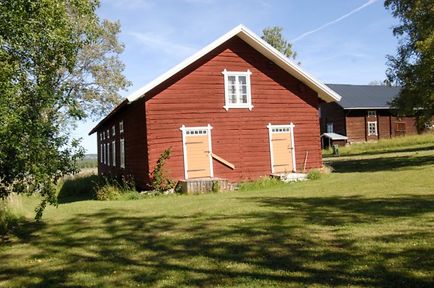 Glasätt 1:7.Timrad, röd byggnad med vita detaljer i två våningar, fönster med vita spröjs och två gula portar.