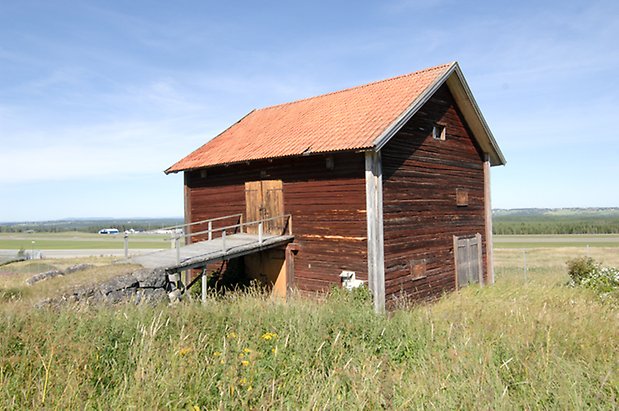 Glasätt 1:7.Byggnad i två våningar i brunt timmer, två gula dubbelportar och en grå dubbelport.