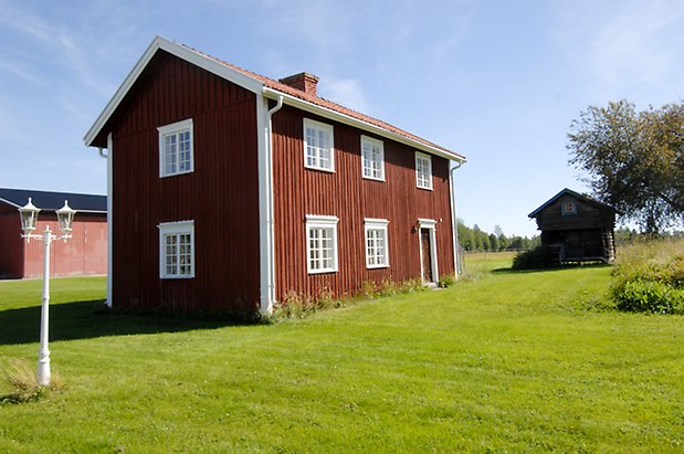 Stocke 4:4. Hus i två våningar i röd panel med vita detaljer, fönster med vita spröjs, skorsten med tegel, brun dörr.