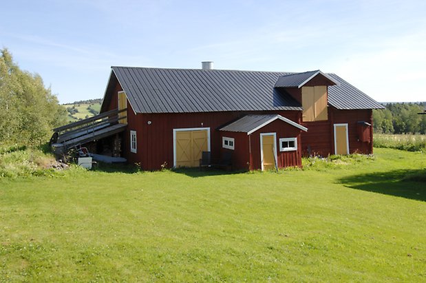 Vagle 4:10. Ladugård i två våningar i röd panel och timmer i två våningar, tre gula dubbelportar och två portar.