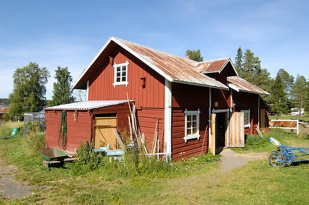 Västbyn1:2. Ladugård i två våningar i röd panel och timmer med vita detaljer, fönster ned vita spröjs. Gul port och dubbelport.