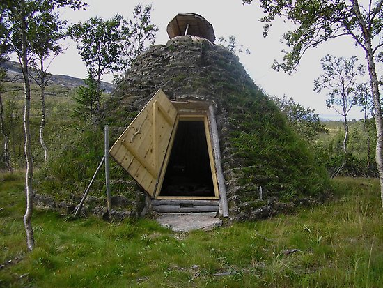 Toppig byggnad som det växer gräs på, trekantig lucka.