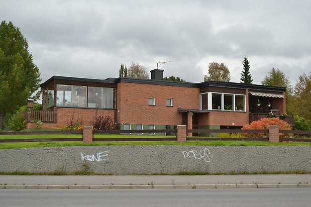 Sänket 1. Bostadshus i brunt tegel med glasveranda.