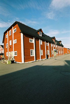 Fältjägaren 6. Stort rött hus i tre våningar med svart tak och vita fönster med spröjs, sett från sidan.