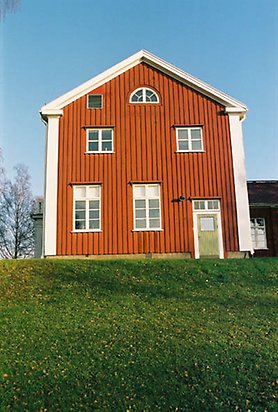 Lugnet 7, hus 81. Rött trähus i två våningar med vita fönster och spröjs och en grön dörr. Sett från sidan.