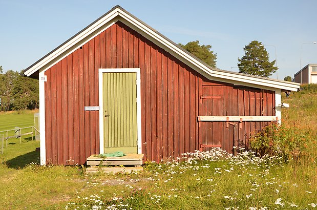 Norr 1:4. Litet, rött trähus med grön dörr.