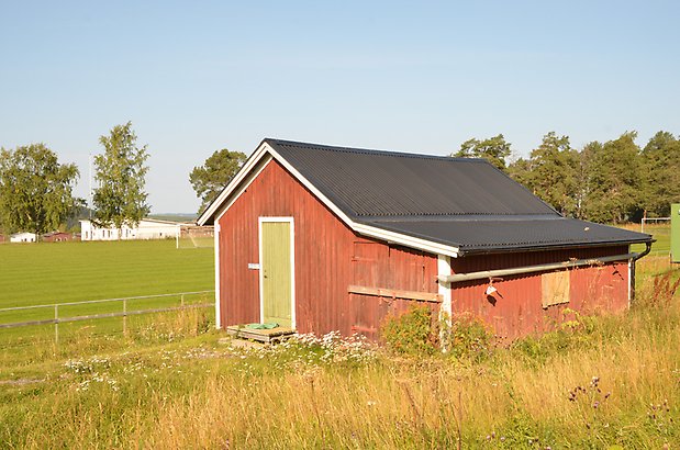 Norr 1:4. Litet rött trä hus med grön dörr.