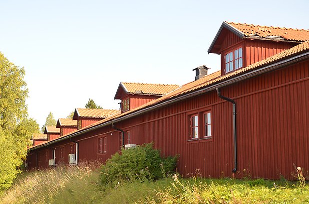 Norr 1:7. Lång byggnad med röd träfasad med takkupor och små fönster.