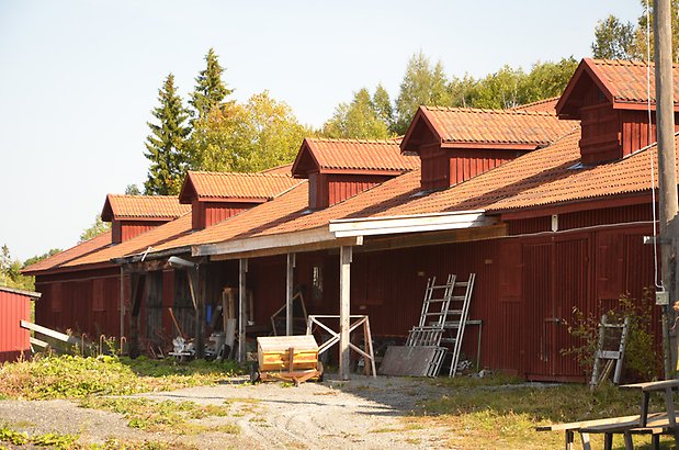 Norr 1:14. Lång byggnad med röd träfasad och takkupor.