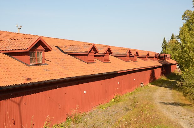 Norr 1:14. Lång byggnad med röd träfasad och takkupor.