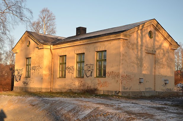 Odenslund 1:6. Byggnad i beige puts med gröna fönster med spröjs.