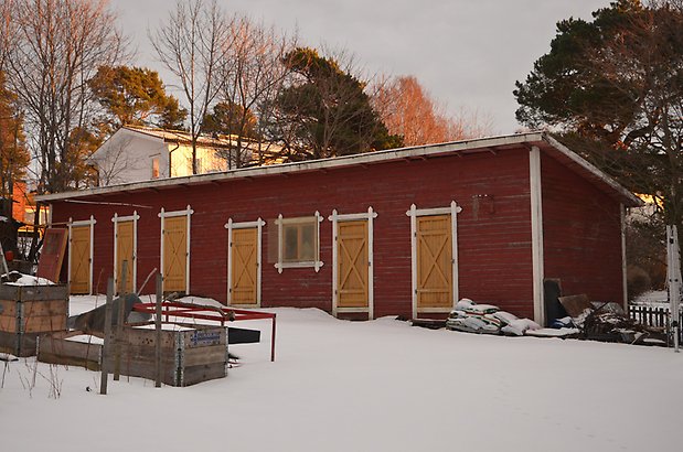 Svärtan 7. Byggnad i röd, liggande träpanel och gula dörrar.