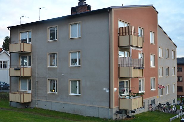 Fritztorp 8. Bostadshus i grå och brun puts, beige balkonger och vita fönster.