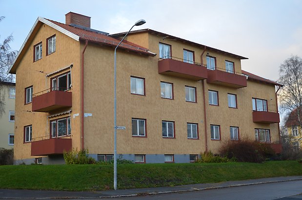 Landssekretereraren 3. Bostadshus i gult tegel med röda balkonger och röda fönster.