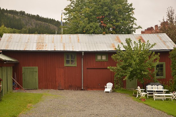 Muraren 3 b. Byggnad i röd panel med grön dörr, röd garageport och gröna fönster med spröjs.