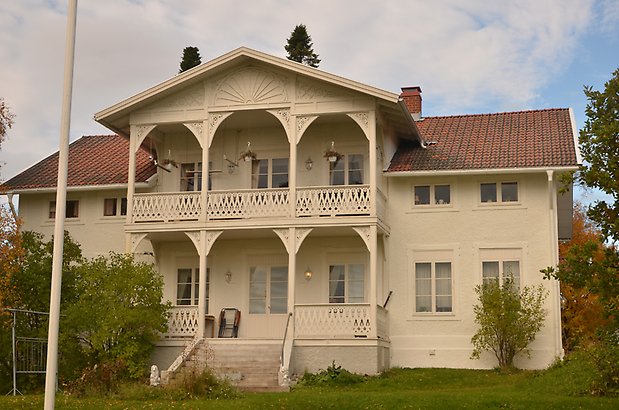 Faktorn 3. Villa i vit puts med veranda och balkong med snickarglädje. 