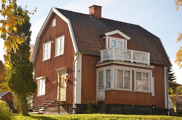 Hyvlaren 7. Villa i brun panel, vita fönster med spröjs och balkong. 