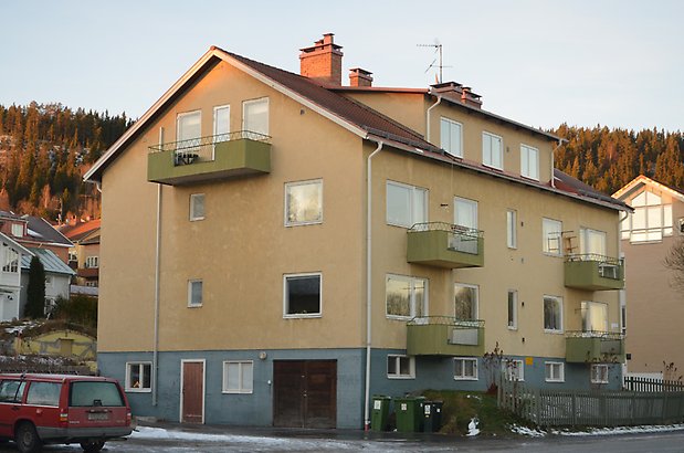 Muraren 2. Bostadshus i tre våningar i med gul puts, nedre våningen är i grå puts, gröna balkonger och vita fönster.