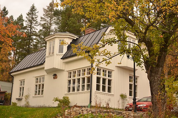 Tullvaktmästaren 1 a. Villa i vit panel, vita fönster med spröjs, svart plåttak och sexkantigt takkupa. 