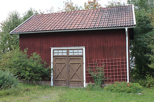 Brunflo-Viken 1:23. Byggnad i röd panel med brun dubbeldörr.