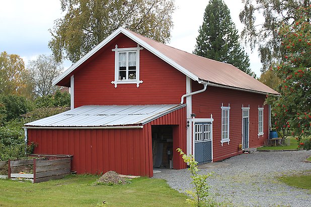 Brunflo-Änge 1:15. Byggnad i röd liggande panel med vita fönster med spröjs och blå portar och dörrar.