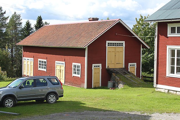 Brunflo-Backen 1:7. Byggnad i röd liggande panel med vita fönster med spröjs och gula portar och dörrar.