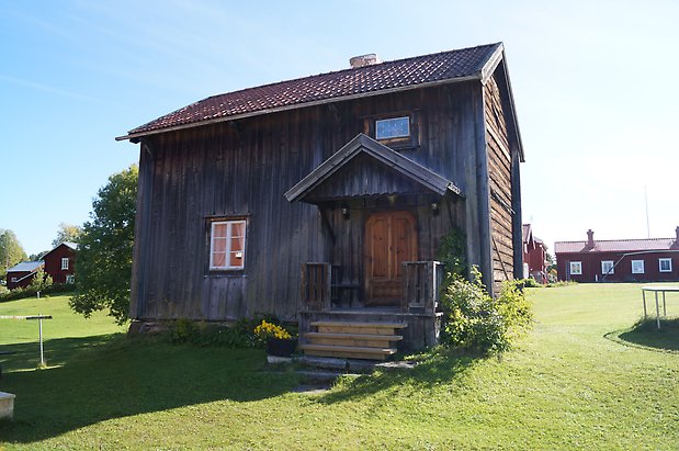 Torvalla 4:50. Hus i två våningar i grå panel, fönster med vita spröjs, förstukvist och brun dubbeldörr.